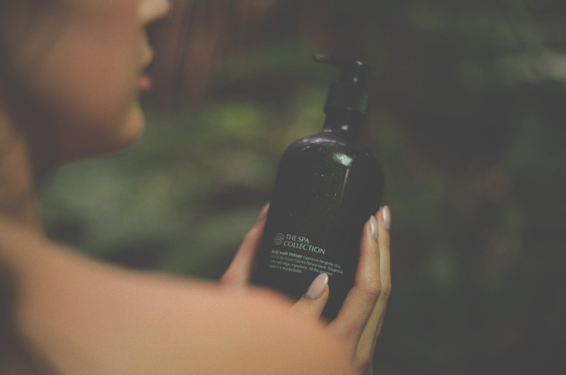The Spa Collection Vetiver body wash held in hand under soft lightning
